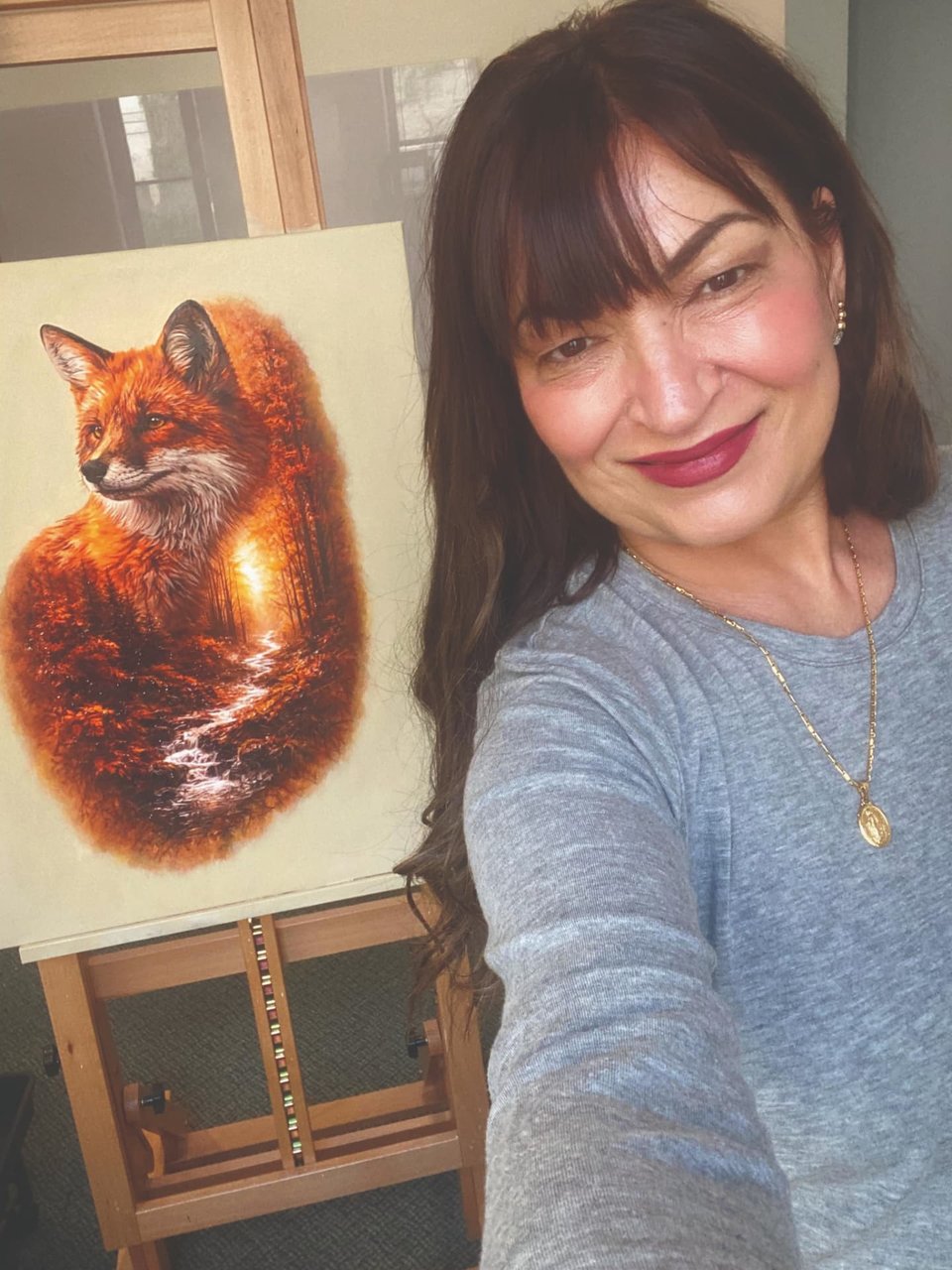 Artist Tamara Bolger smiling beside her painting of a red fox in her studio