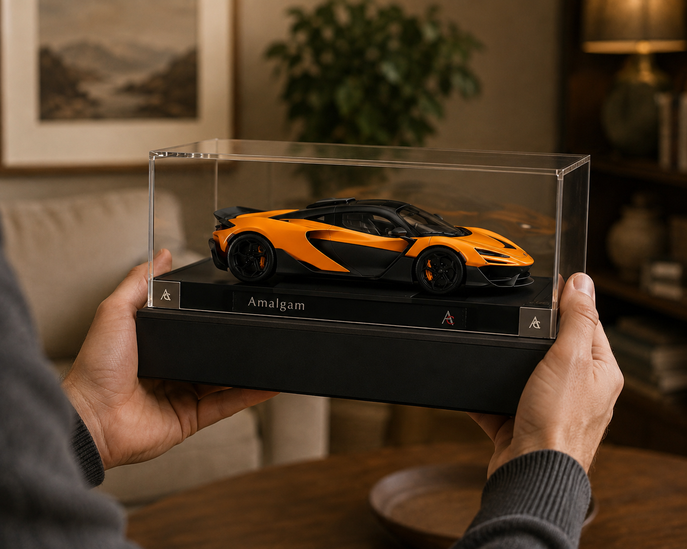 Hands holding an Amalgam McLaren memorial sculpture in a clear display case